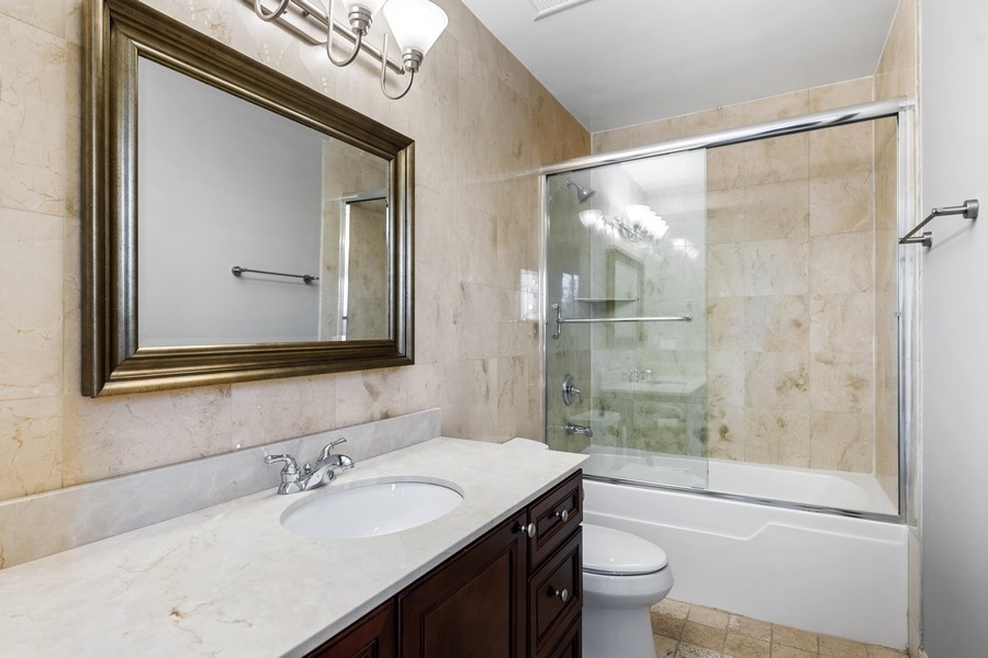 2340 West Adams Street, Unit 33 Chicago, IL 60612 - Photo 15 of 17 a bathroom with a granite countertop sink toilet a mirror and shower