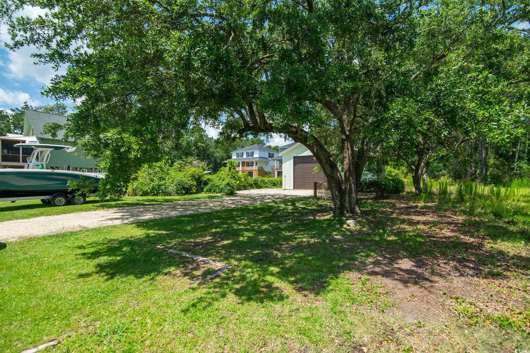 127 Brown Pelican Loop Pawleys Island, SC 29585 - Photo 29 of 31 View of green lawn featuring a garage and driveway