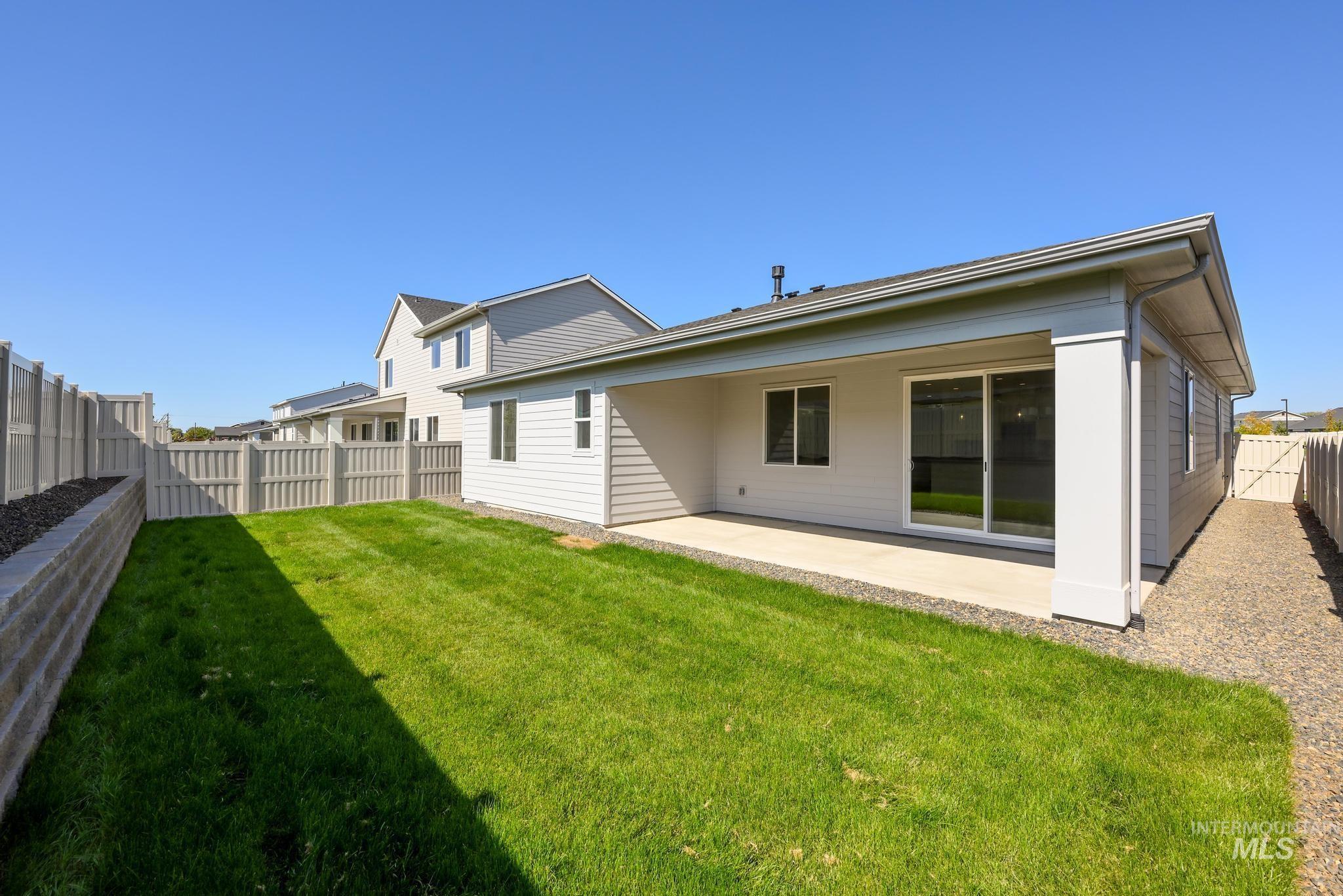 14880 Wing Spread Drive Caldwell, ID 83607 - Photo 12 of 12 Rear exterior with a covered concrete patio, sliding glass door, and a manicured lawn