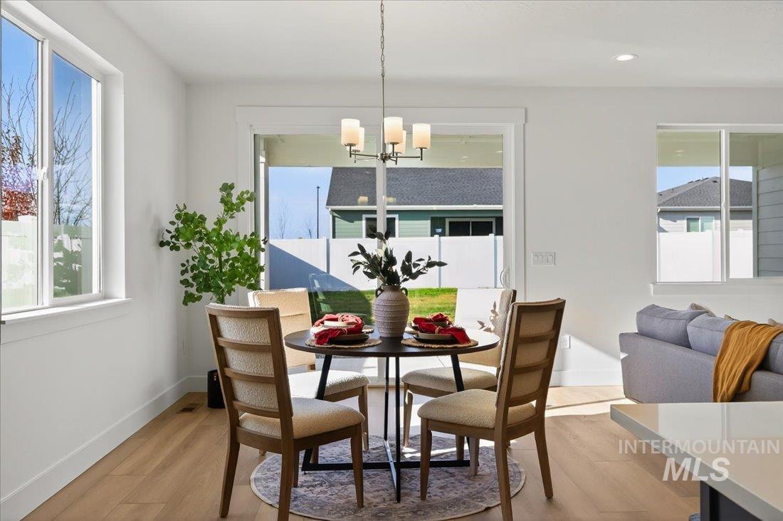 14880 Wing Spread Drive Caldwell, ID 83607 - Photo 5 of 12 Dining area featuring light wood-finish flooring, white walls, and a contemporary chandelier