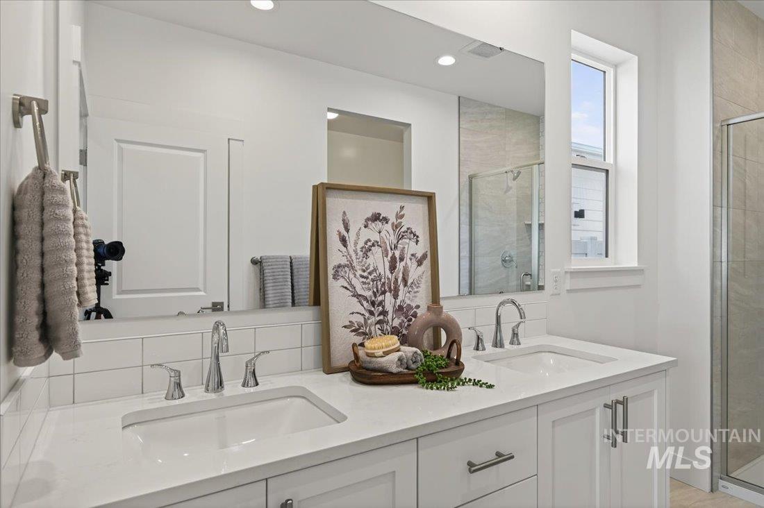 14880 Wing Spread Drive Caldwell, ID 83607 - Photo 8 of 12 Dual vanity with integrated sinks, white cabinetry, chrome fixtures, and a subway tile backsplash