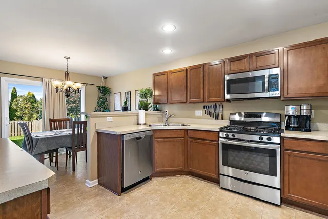 a kitchen with stainless steel appliances granite countertop a stove top oven a sink dishwasher a dining table and chairs with wooden floor