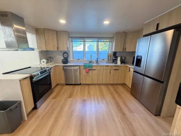 a kitchen with stainless steel appliances a refrigerator a sink a stove a refrigerator cabinets and wooden floor