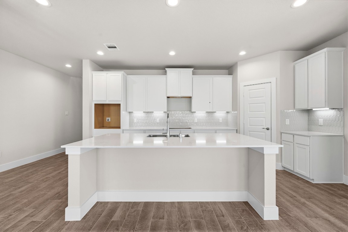 2137 Golden Spruce Court Conroe, TX 77301 - Photo 2 of 41 a kitchen with kitchen island a sink a stove a refrigerator and white cabinets