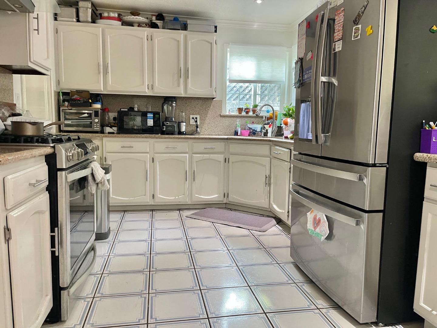 3223 Spring Street Redwood City, CA 94063 - Photo 7 of 14 a kitchen with stainless steel appliances a refrigerator sink and cabinets