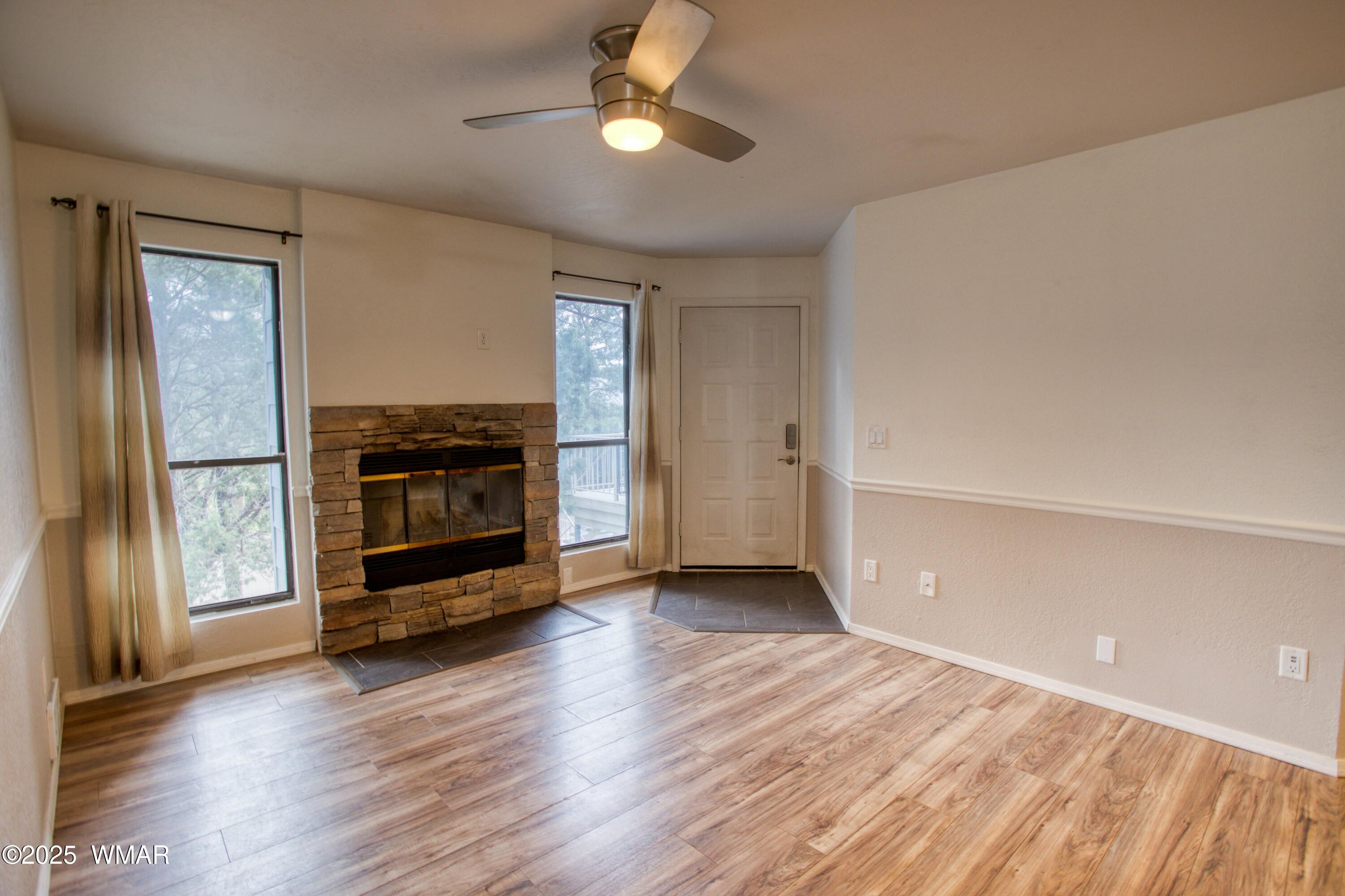 2700 South White Mountain Road, Unit 122 Show Low, AZ 85901 - Photo 2 of 25 wooden floor in an empty room with a fireplace