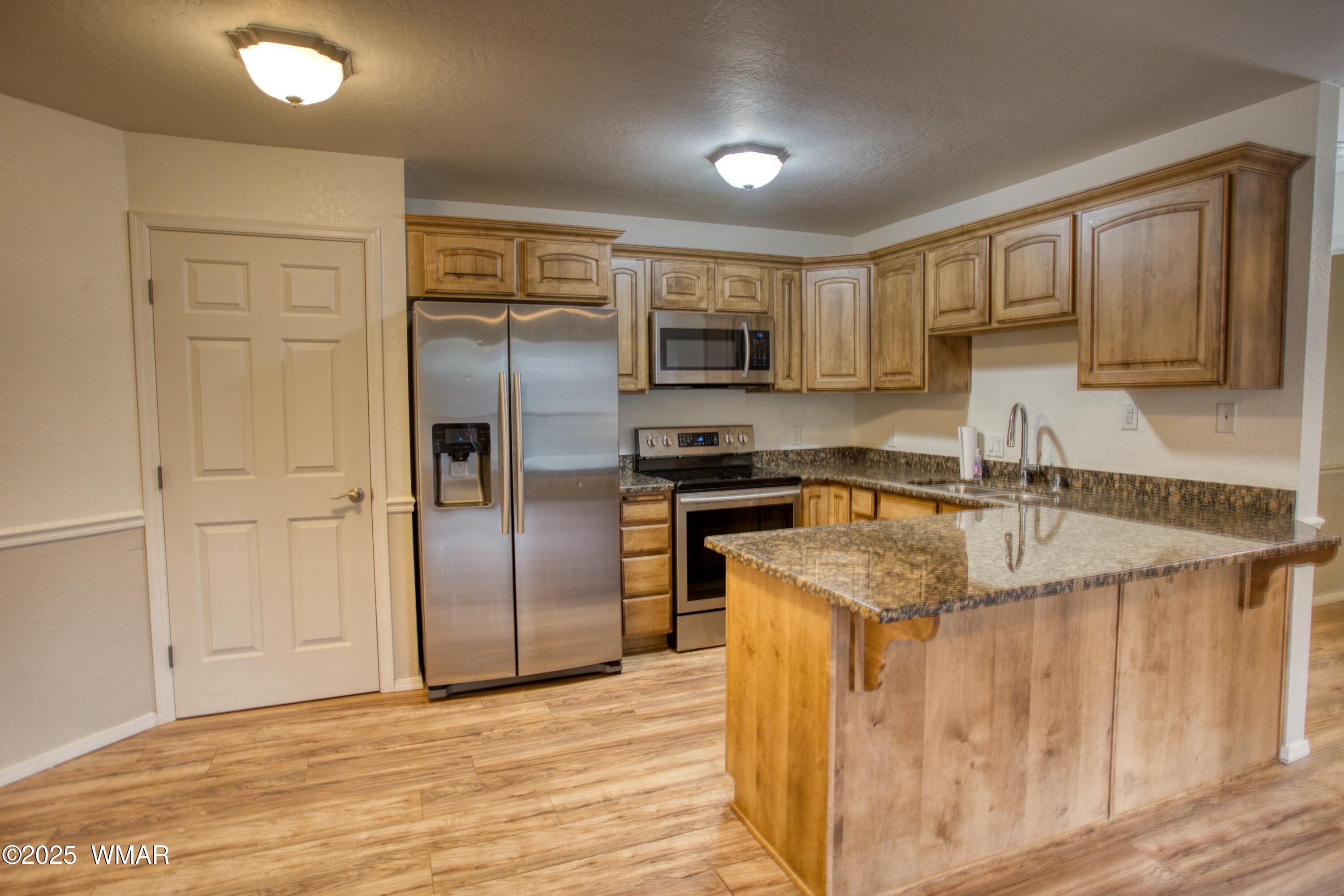 2700 South White Mountain Road, Unit 122 Show Low, AZ 85901 - Photo 6 of 25 a kitchen with stainless steel appliances granite countertop a sink stove and refrigerator