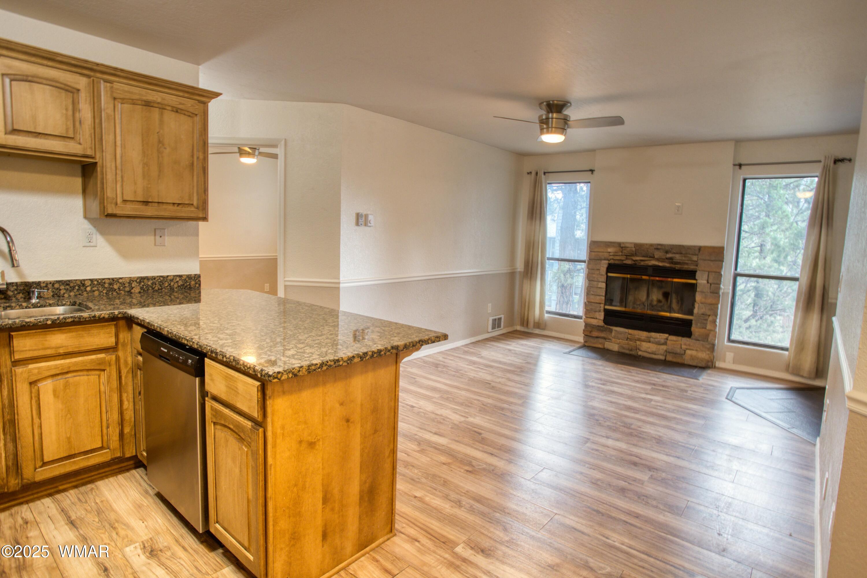 2700 South White Mountain Road, Unit 122 Show Low, AZ 85901 - Photo 8 of 25 a kitchen with granite countertop a stove top oven a sink dishwasher and a fireplace with wooden floor