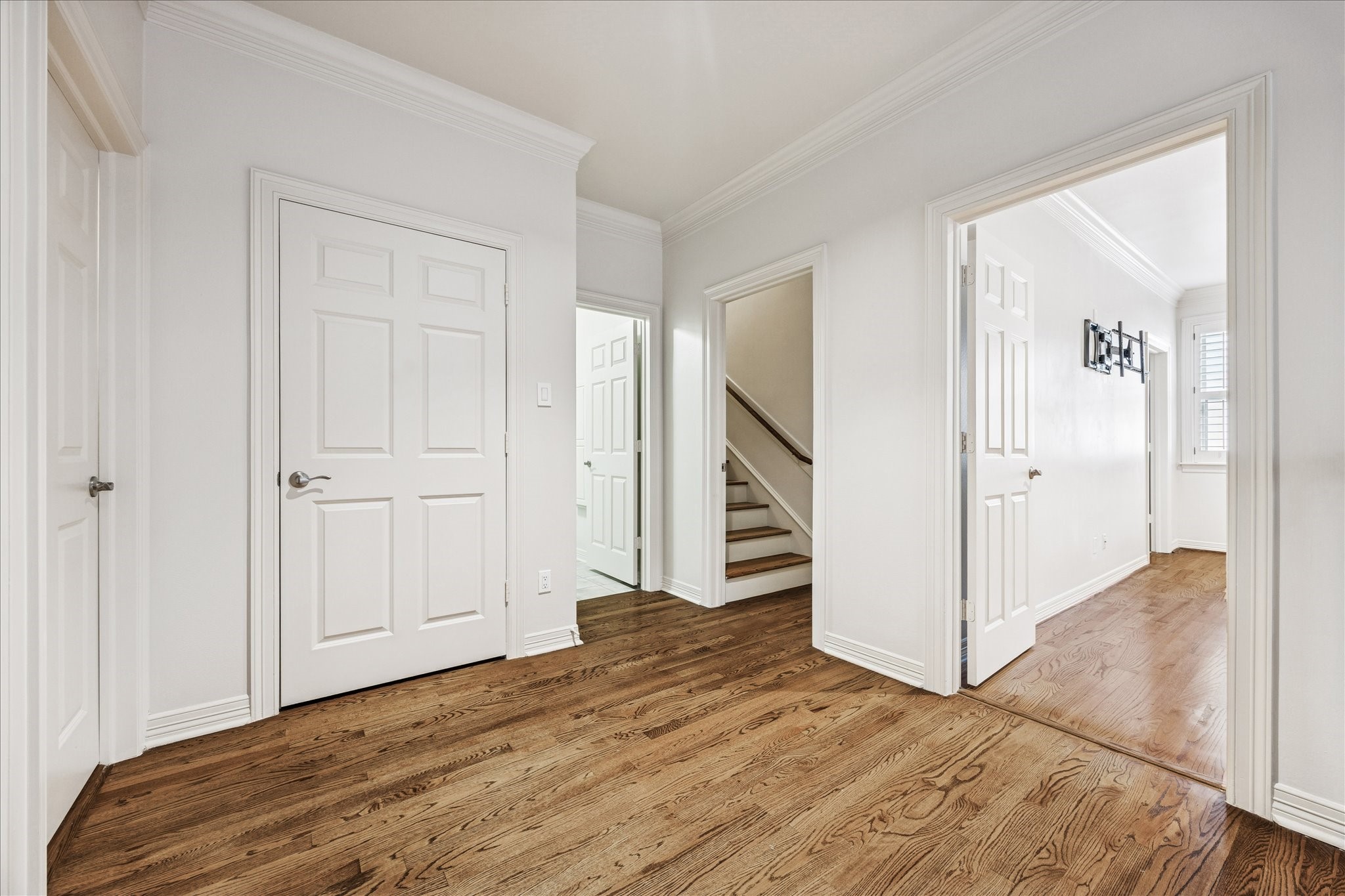 5823 Augusta Court Houston, TX 77057 - Photo 28 of 44 This photo showcases a bright and spacious landing at the top of the second floor with polished hardwood floors, white walls, and multiple doors leading to different rooms and closets. An additional staircase with wooden steps provides access to the third level.