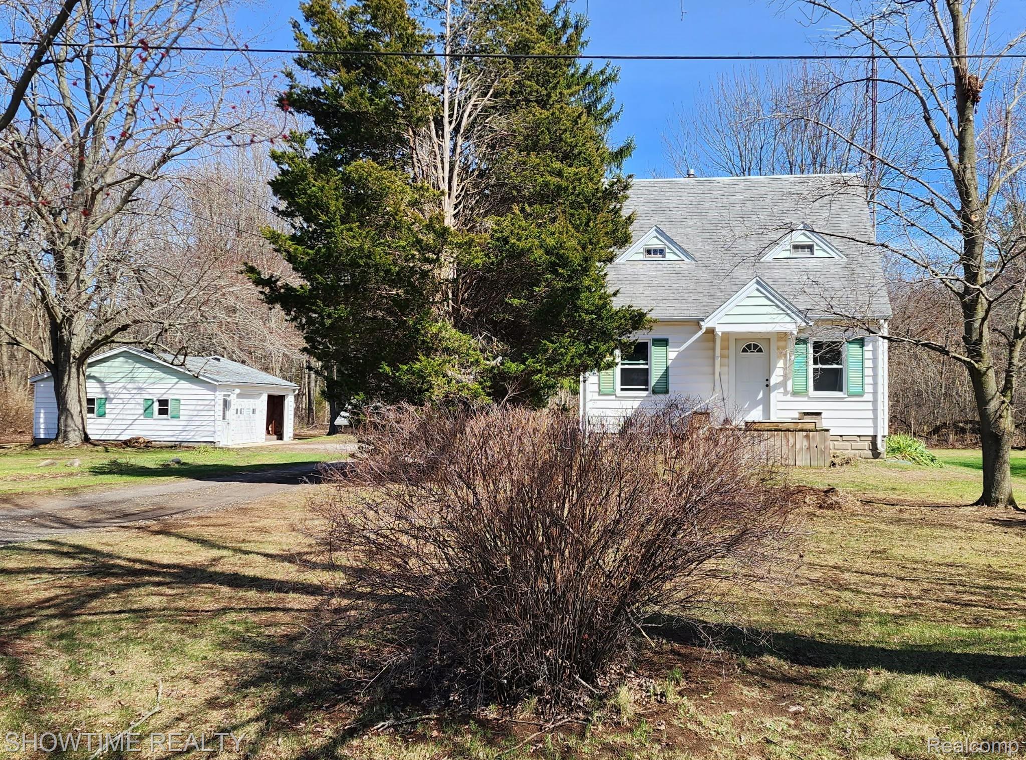 2970 Range Road Port Huron, MI 48060 - Photo 1 of 31 White siding residence featuring green window shutters, a front porch with railing, and an arched entry door