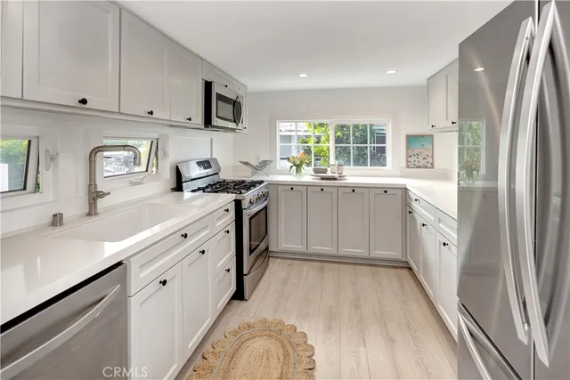 a kitchen with granite countertop a sink stove refrigerator and cabinets