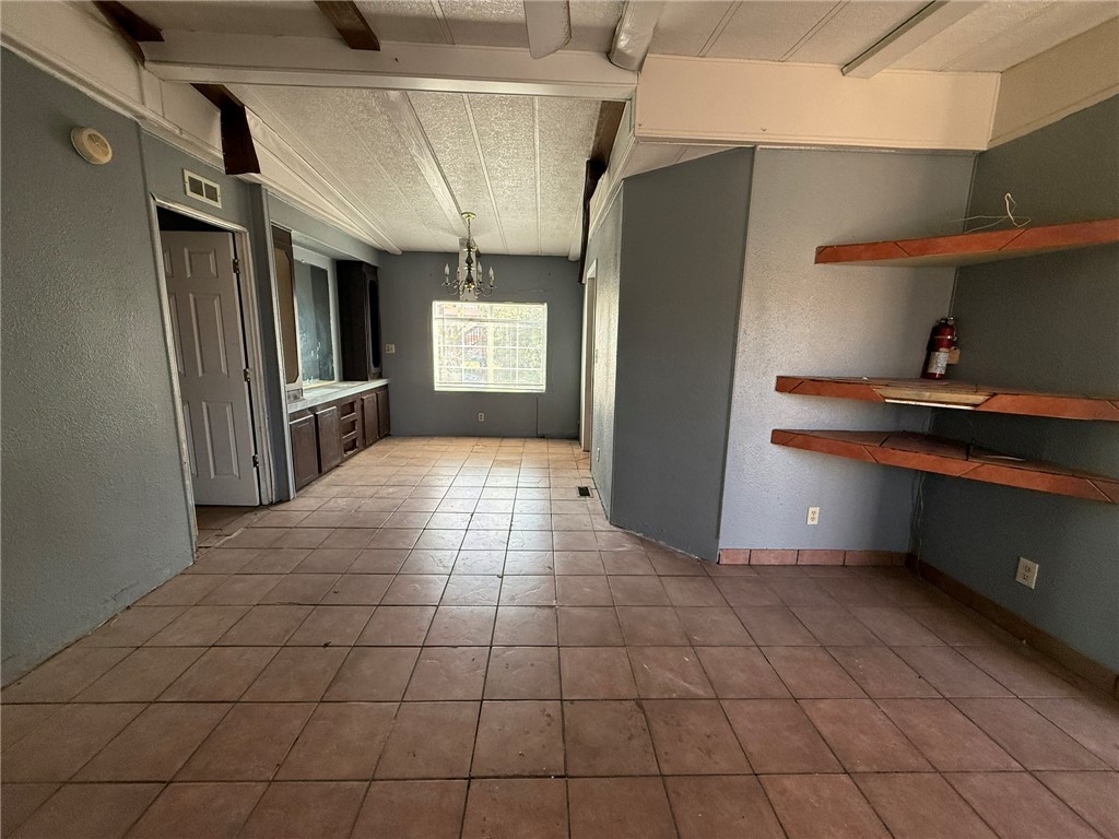 1629 Ramar Road Bullhead City, AZ 86442 - Photo 11 of 29 Kitchen with a chandelier, a textured wall, hanging light fixtures, beamed ceiling, and light tile patterned floors