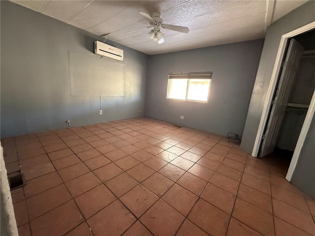 1629 Ramar Road Bullhead City, AZ 86442 - Photo 12 of 29 Unfurnished bedroom featuring tile patterned floors, a ceiling fan, and an AC wall unit