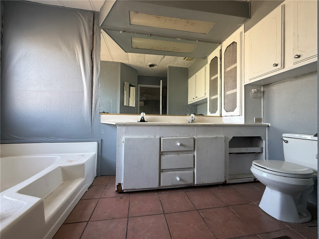 1629 Ramar Road Bullhead City, AZ 86442 - Photo 14 of 29 Bathroom with double vanity, dark tile patterned flooring, and a bath
