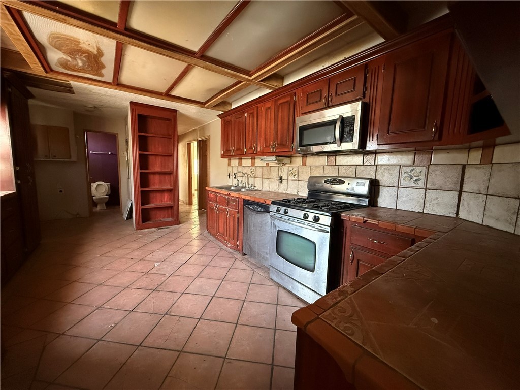 1629 Ramar Road Bullhead City, AZ 86442 - Photo 17 of 29 Kitchen featuring stainless steel appliances, tile counters, open shelves, light tile patterned flooring, and backsplash