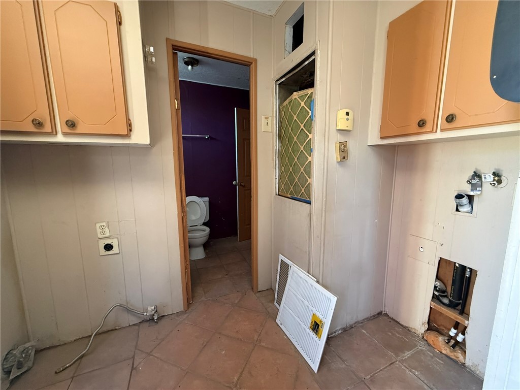 1629 Ramar Road Bullhead City, AZ 86442 - Photo 20 of 29 Laundry area with cabinet space, hookup for an electric dryer, washer hookup, wood walls, and light tile patterned floors