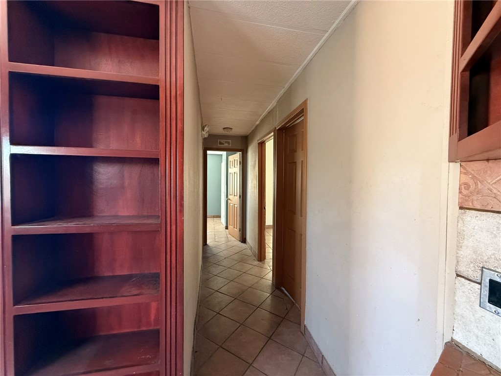 1629 Ramar Road Bullhead City, AZ 86442 - Photo 21 of 29 Hallway featuring light tile patterned floors, ornamental molding, and a textured ceiling