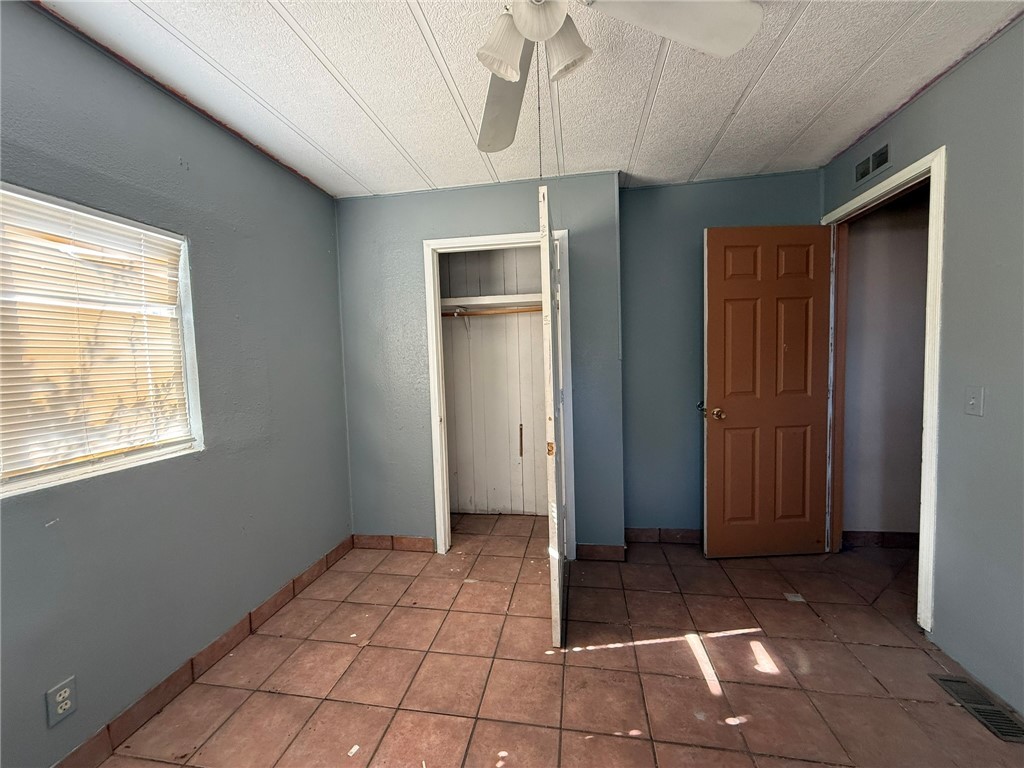 1629 Ramar Road Bullhead City, AZ 86442 - Photo 24 of 29 Unfurnished bedroom featuring a closet, ceiling fan, a textured ceiling, and light tile patterned floors