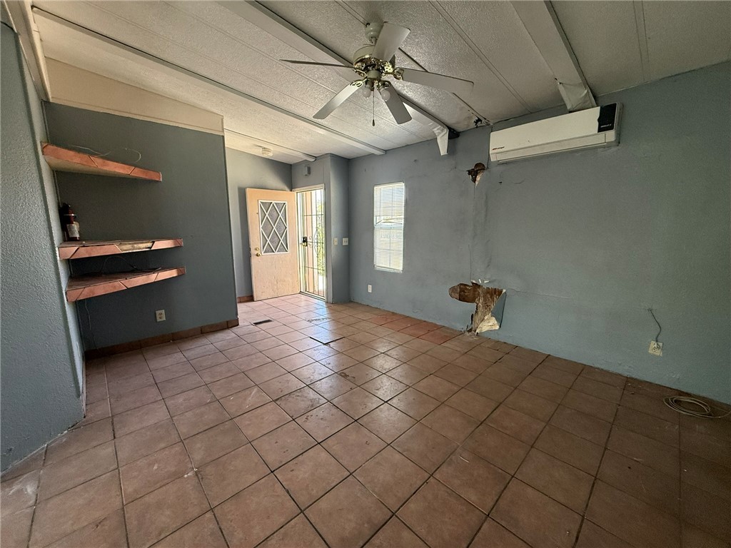 1629 Ramar Road Bullhead City, AZ 86442 - Photo 10 of 29 Spare room with ceiling fan, light tile patterned floors, a wall mounted air conditioner, and a textured ceiling