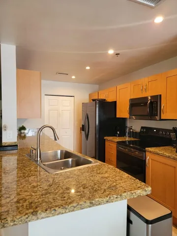 a kitchen with stainless steel appliances granite countertop a sink a stove and refrigerator