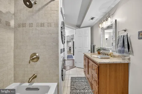 a bathroom with a granite countertop sink a toilet a mirror and shower