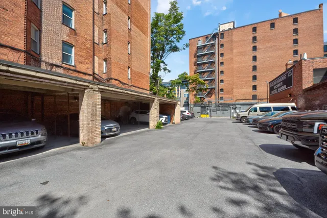 a front view of a building with lot of cars parked and a car parked in front of it