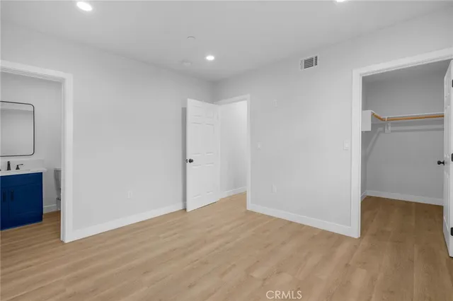 a view of an empty room with wooden floor and a bathroom