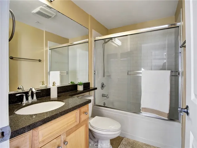 a bathroom with a granite countertop sink toilet and shower