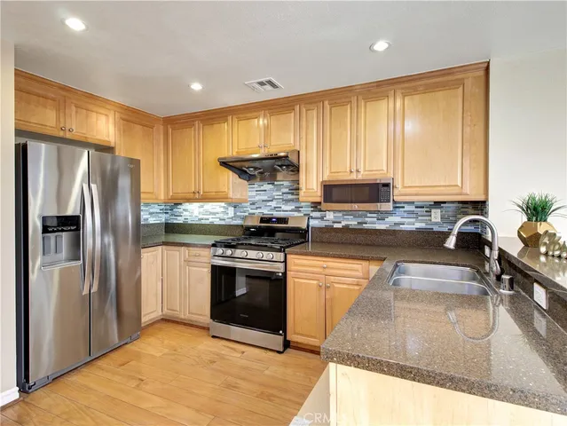 a kitchen with stainless steel appliances granite countertop a refrigerator a stove and a sink