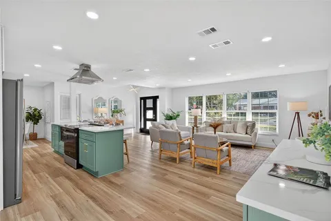 a kitchen with stainless steel appliances a refrigerator a sink a stove a dining table and chairs