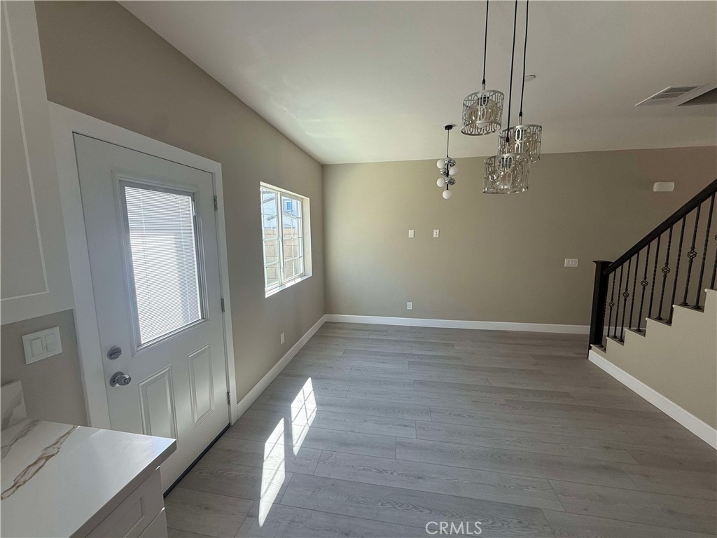 15909 Merrill Avenue, Unit 9 Fontana, CA 92335 - Photo 4 of 19 a view of an empty room with wooden floor and a chandelier