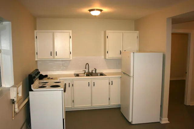 a kitchen with a sink a stove a refrigerator and white cabinets