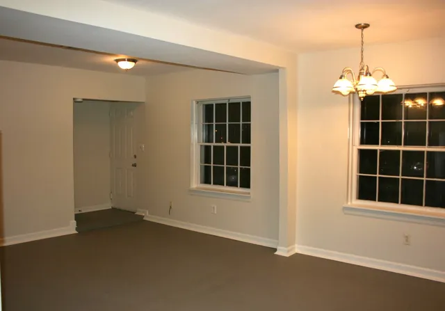 a view of an empty room with a window and chandelier fan