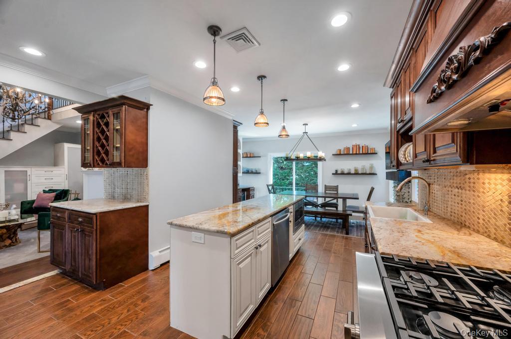 357 Wynsum Avenue Merrick, NY 11566 - Photo 17 of 40 a kitchen with stainless steel appliances granite countertop a stove top oven a sink dishwasher a dining table and chairs with wooden floor