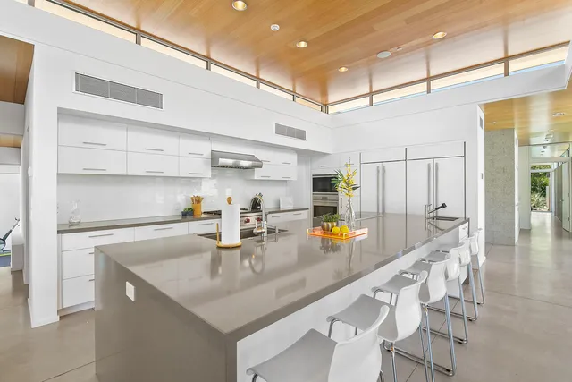 a dining room with large window chairs and a kitchen view