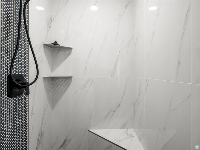 1159 North Broad Hollow Road Garden City, UT 84028 - Photo 30 of 55 Primary Shower with white vein-patterned wall tiling, a black hexagonal tile accent wall, built-in corner shelves, a built-in shower bench, and a matte black shower fixture