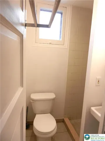 a white toilet sitting next to a small window