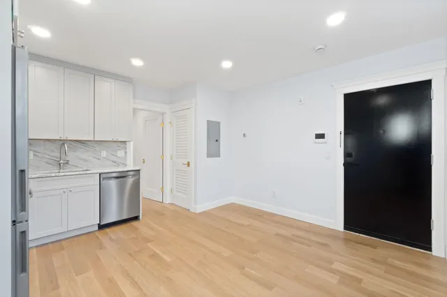 a kitchen with a refrigerator and white cabinets
