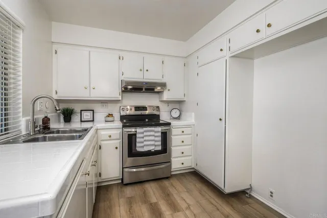 a kitchen with stainless steel appliances a sink cabinets and wooden floor