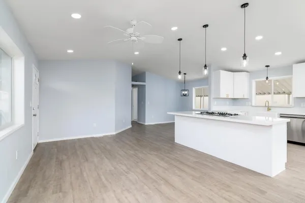 a large kitchen with granite countertop a large counter top a sink stainless steel appliances and cabinets