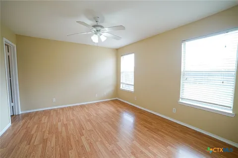 a view of an empty room with wooden floor and a window