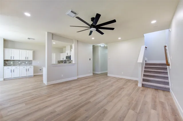 a view of a kitchen with wooden floor and a ceiling fan