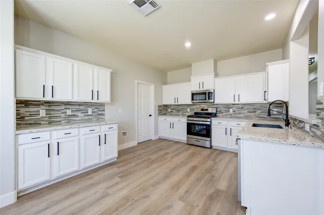a kitchen with granite countertop white cabinets and white stainless steel appliances