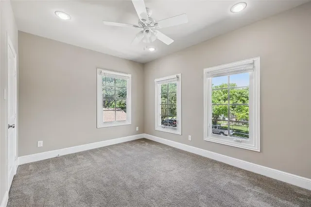 an empty room with windows and chandelier fan