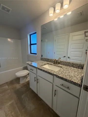 a bathroom with a granite countertop sink mirror vanity and toilet