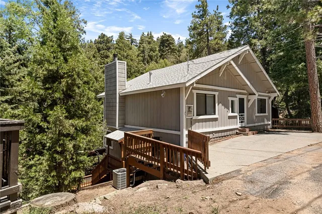 a view of house with yard outdoor seating and covered with trees