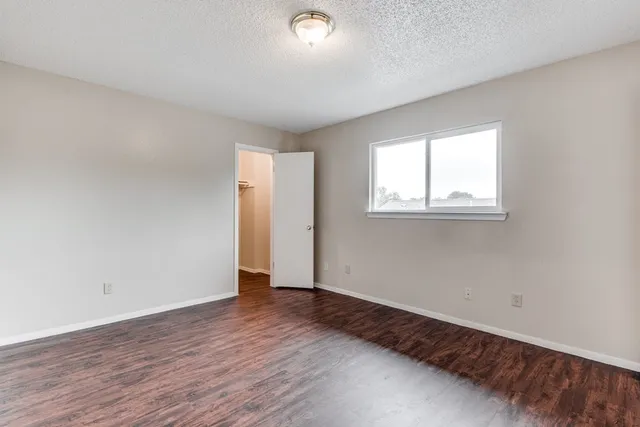 an empty room with wooden floor and windows