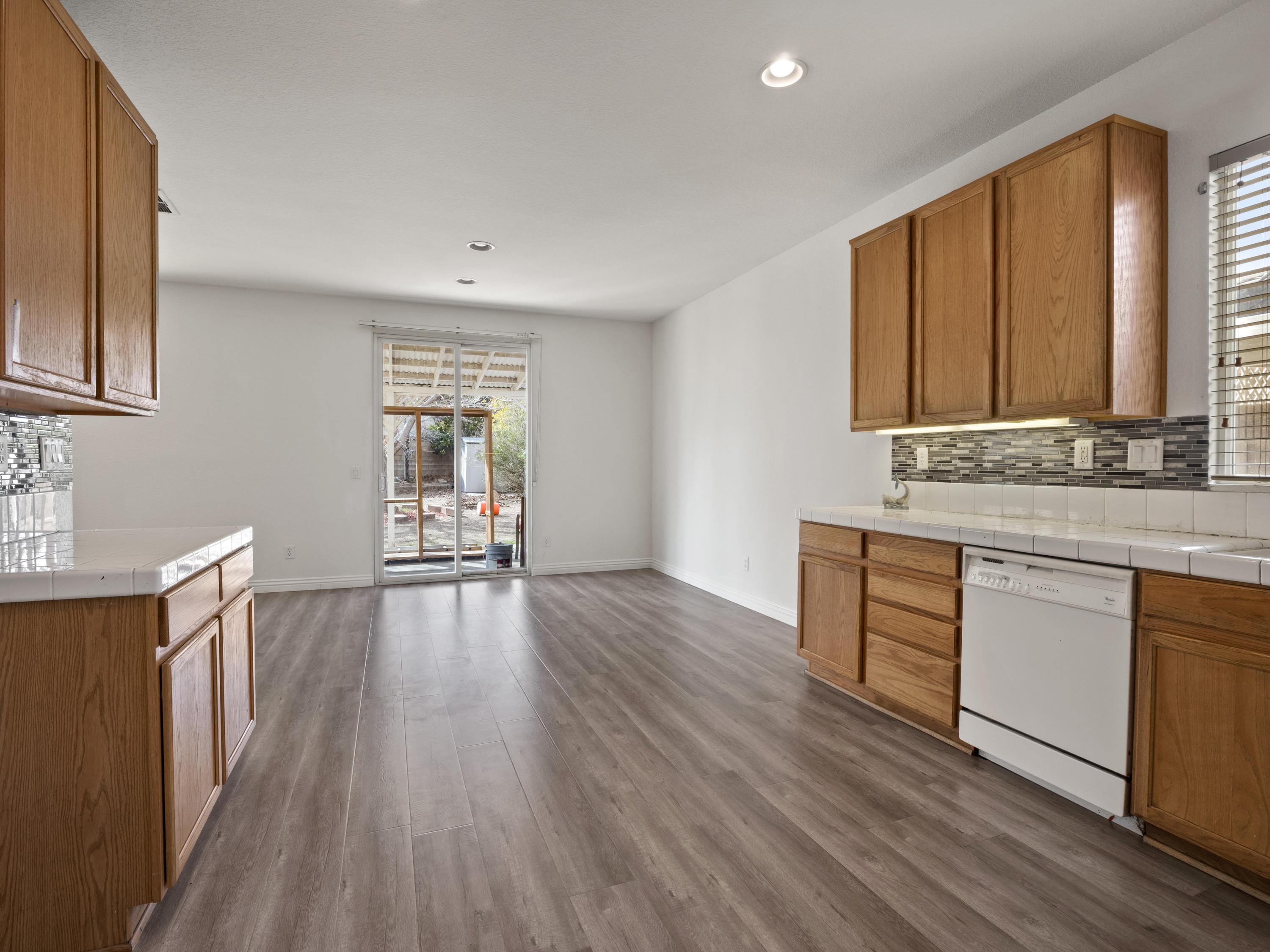 43635 Dana Drive Lancaster, CA 93535 - Photo 11 of 20 a kitchen with granite countertop wooden floors a sink a stove and white cabinets with wooden floor