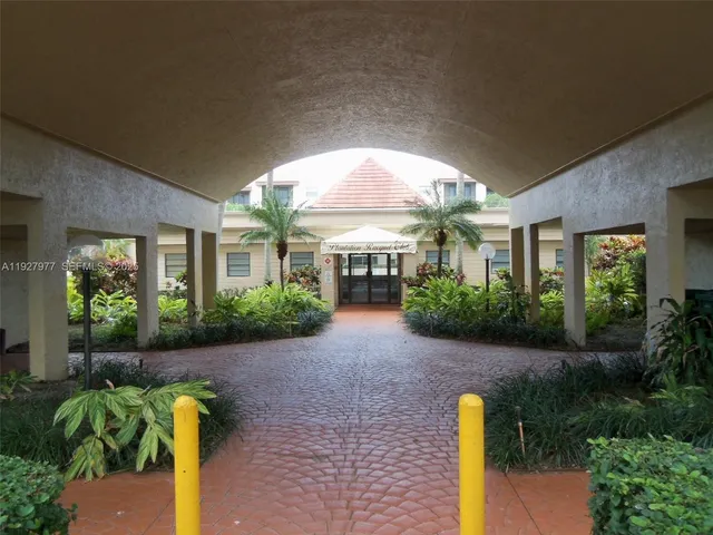 a view of a house with brick walls plants and large tree