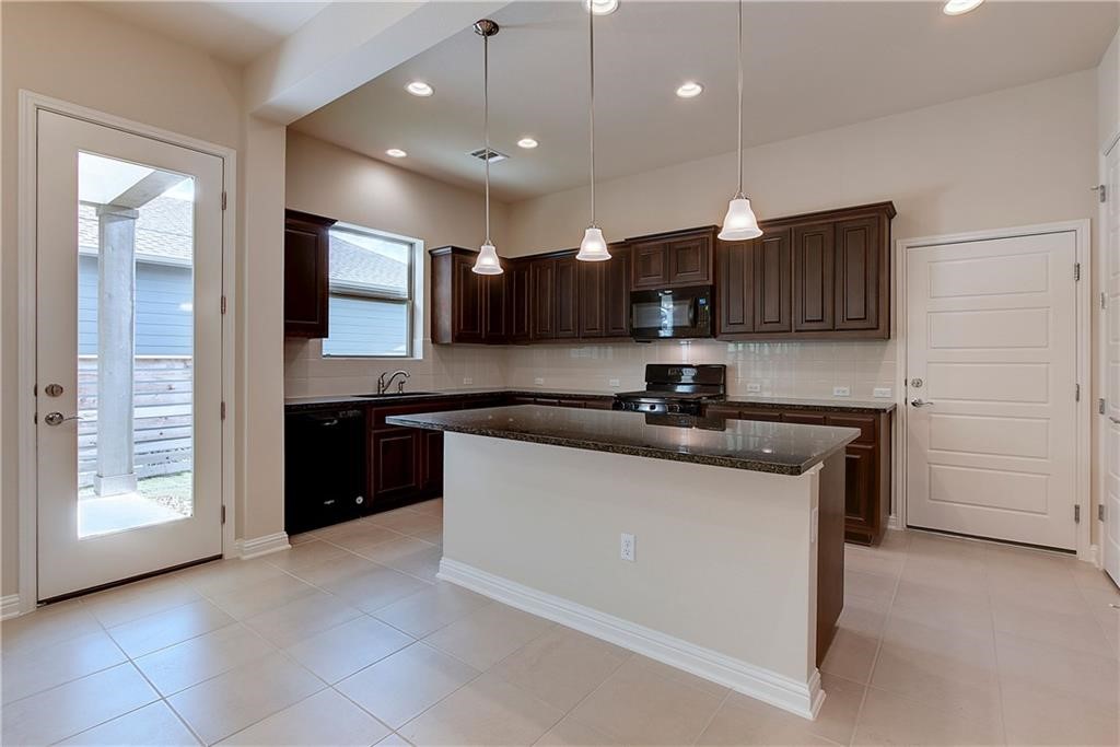 6907 Idea Road Austin, TX 78741 - Photo 7 of 29 Kitchen area with island, dark cabinets, and granite counter tops